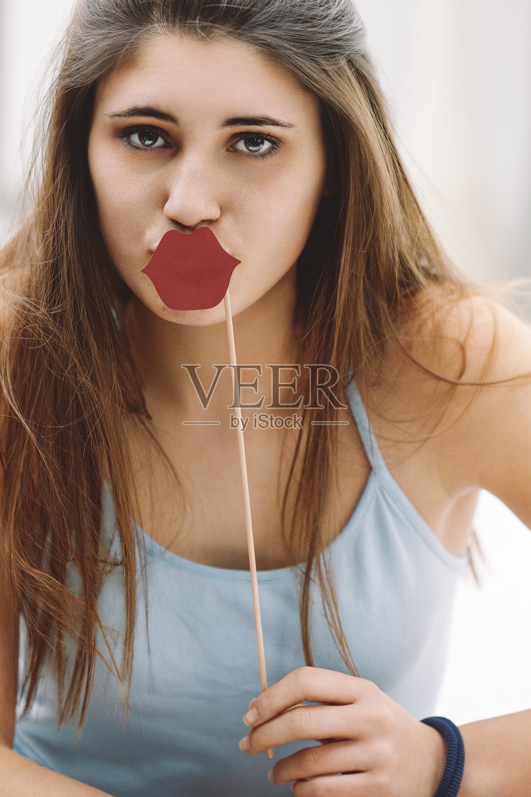 年轻女性手持搞笑嘴唇道具在拍照亭前摆姿势照片摄影图片