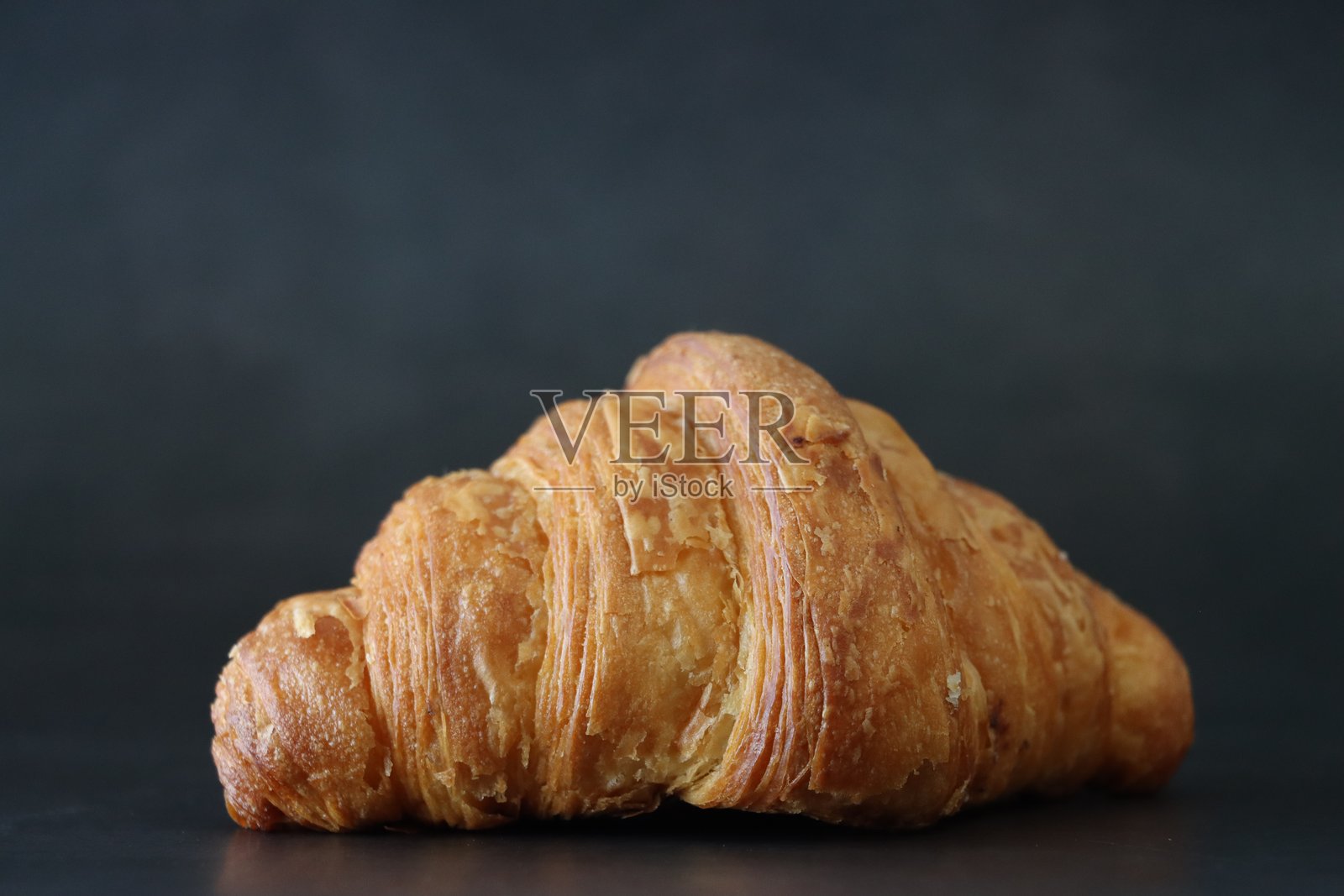 新鲜出炉的早餐糕点特写，全黄油可颂，黑色背景，前景聚焦，留白空间照片摄影图片