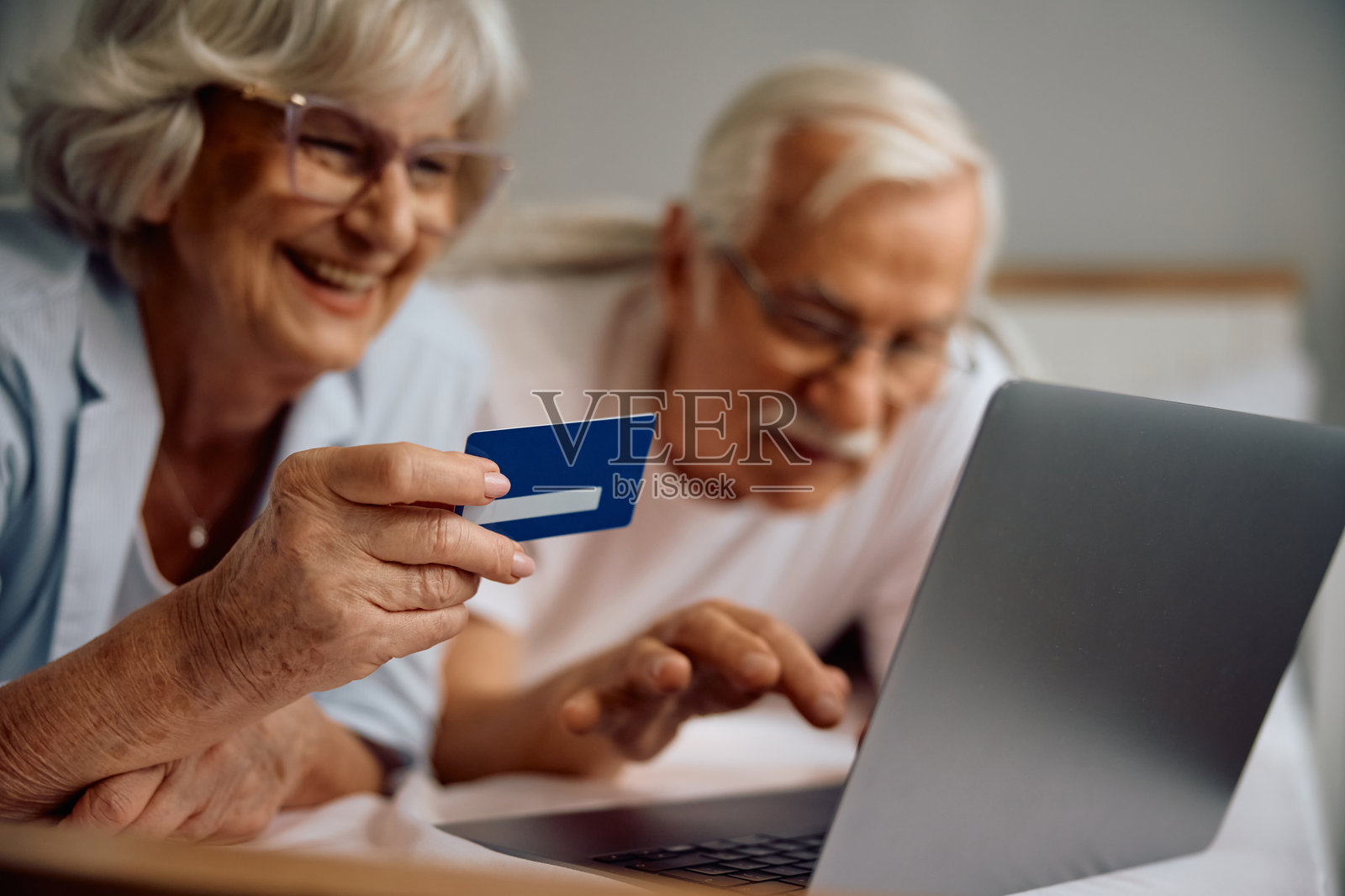 老年夫妇使用信用卡和笔记本电脑进行在线银行业务的特写镜头。照片摄影图片