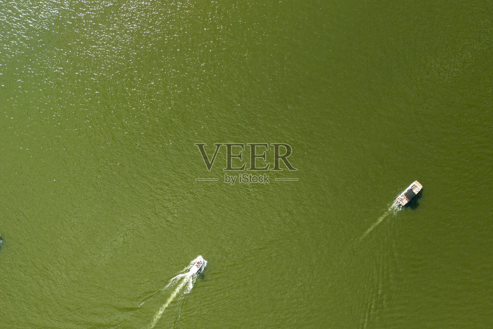 鸟瞰视角下的船只在绿色水域中航行，展现宁静的自然风光。非常适合旅行和休闲主题。照片摄影图片