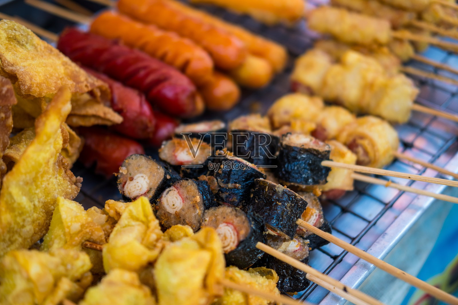 路边出售的各种炸串、肉丸和香肠。照片摄影图片