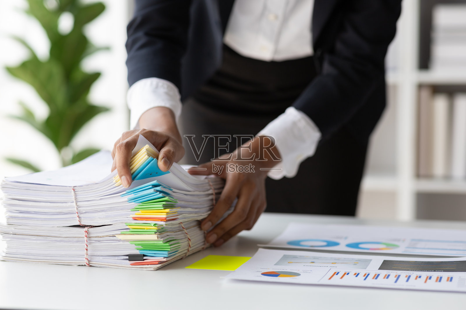 女商人在繁忙的办公桌上处理纸质文件，查找和检查未完成的文件夹。照片摄影图片