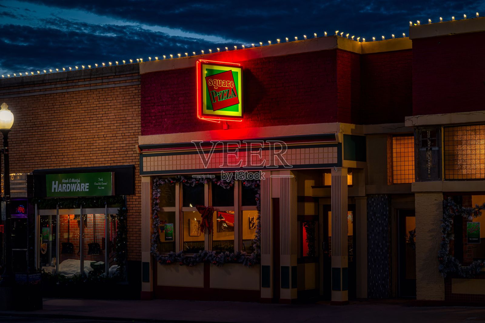 小镇街道的夜景，旁边有一家比萨餐厅和一家五金店照片摄影图片