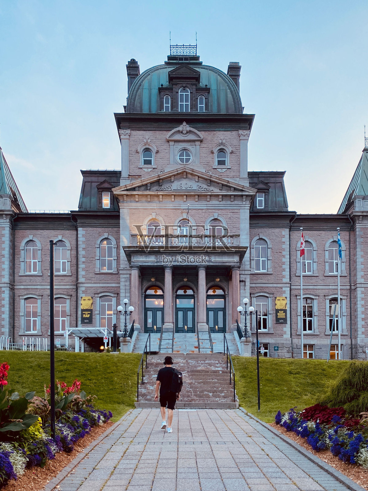 一名男子走向魁北克市的历史悠久的市政厅，天空湛蓝。照片摄影图片