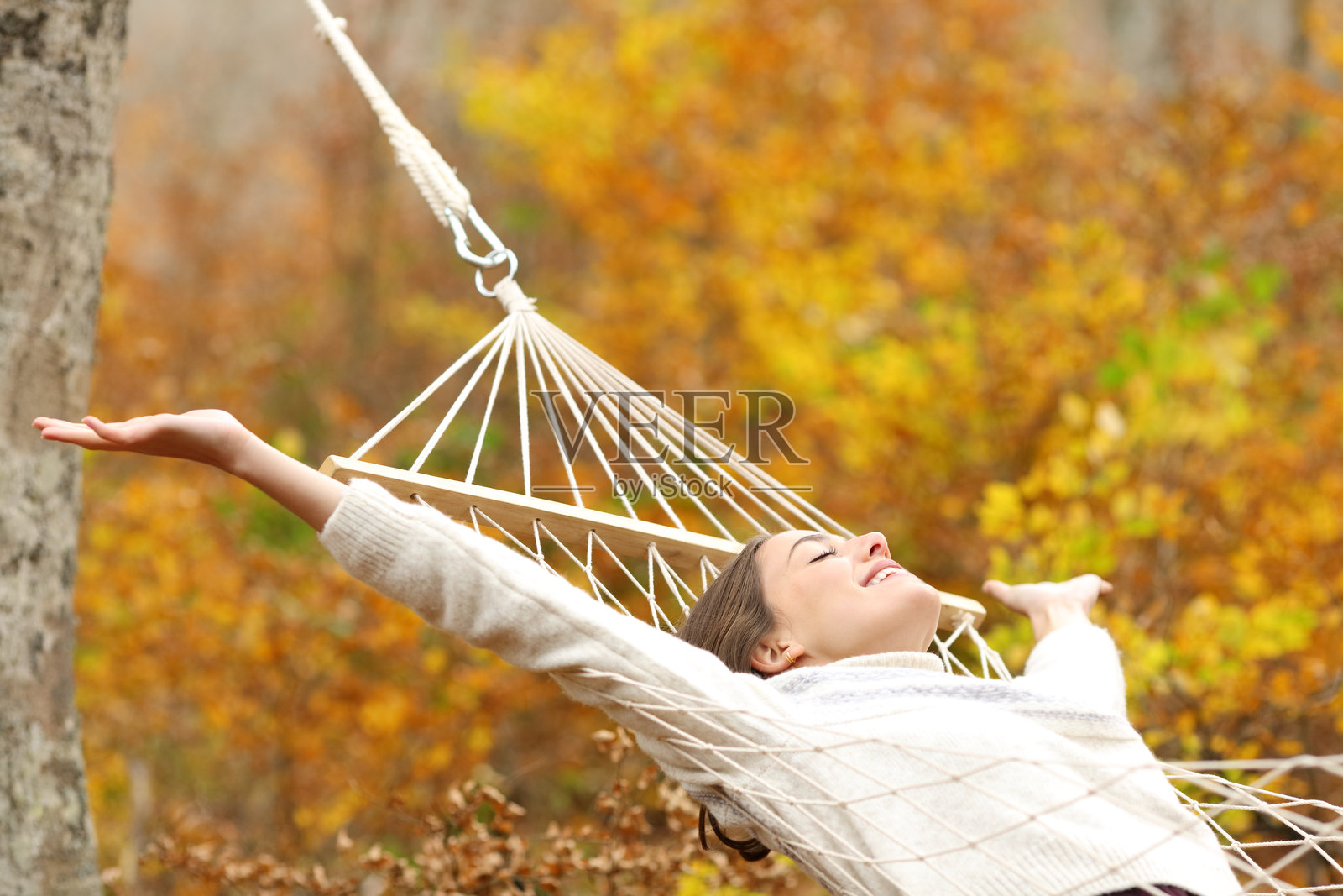 快乐的女人在吊床上庆祝秋季假期照片摄影图片