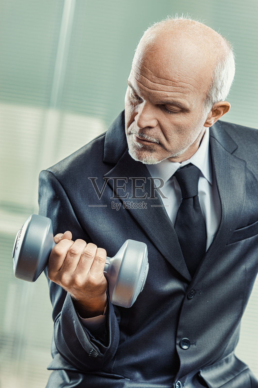 严肃的商人在办公室举哑铃照片摄影图片