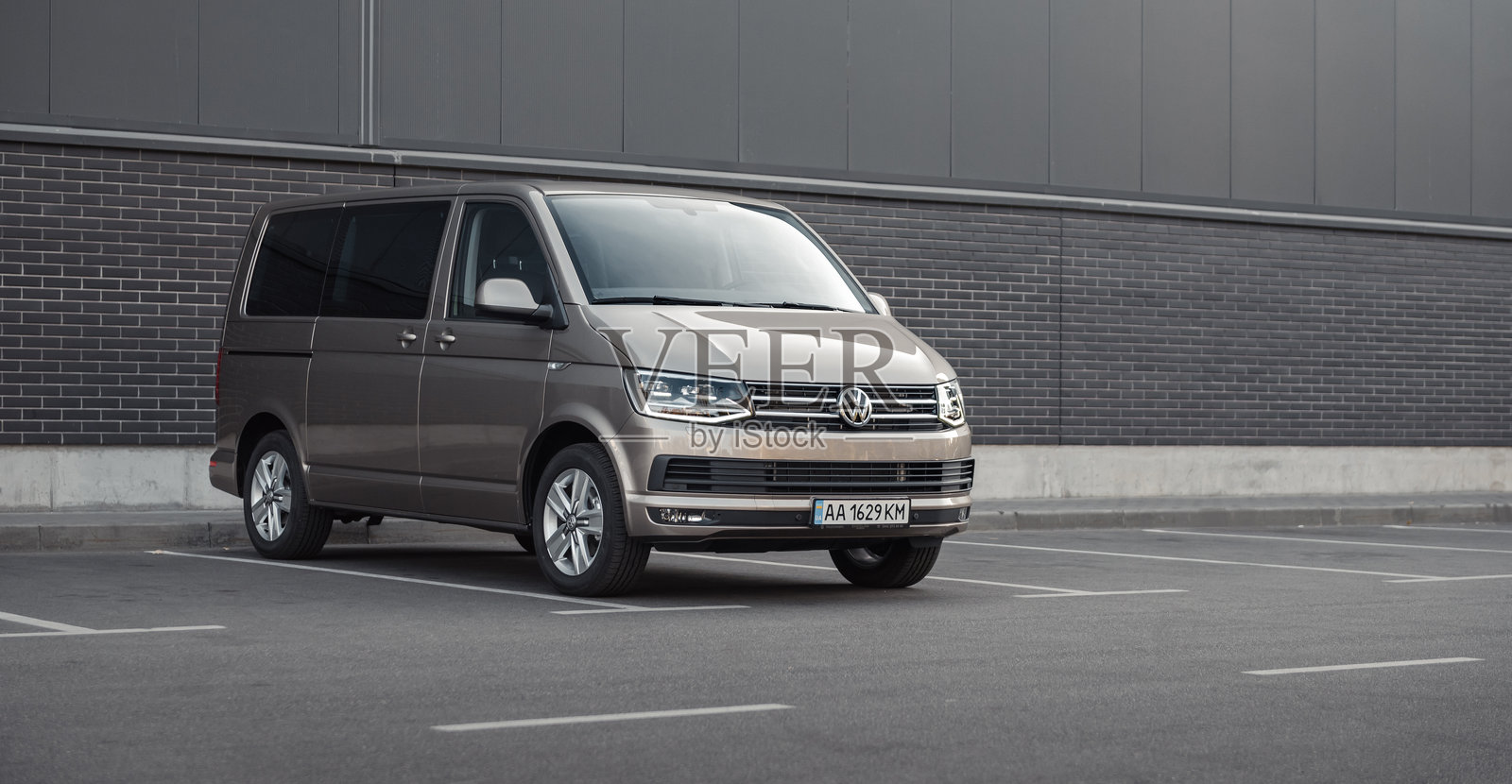 棕色大众运输车停在灰色墙壁前。照片摄影图片