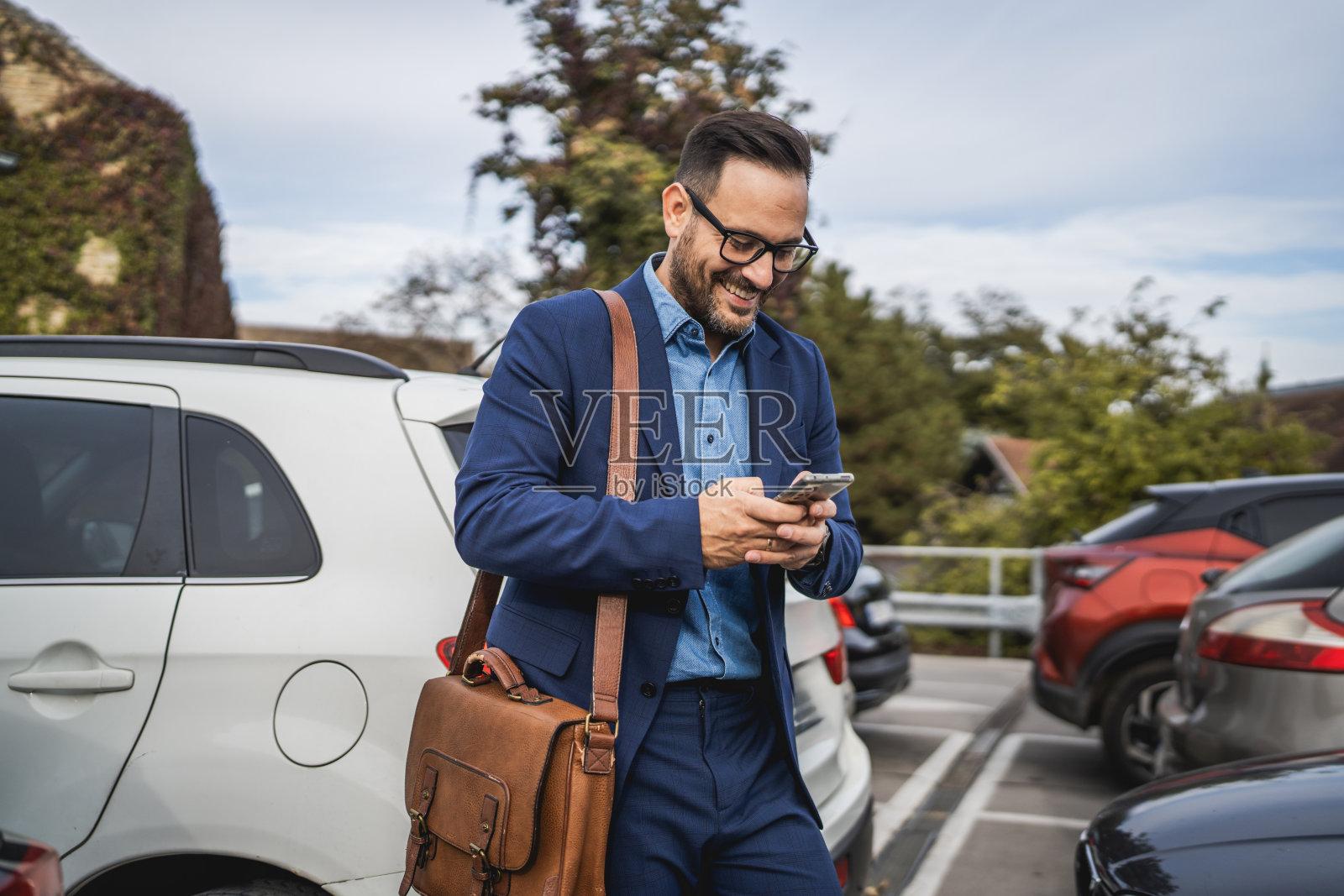 成年商人在停车场站着使用手机照片摄影图片