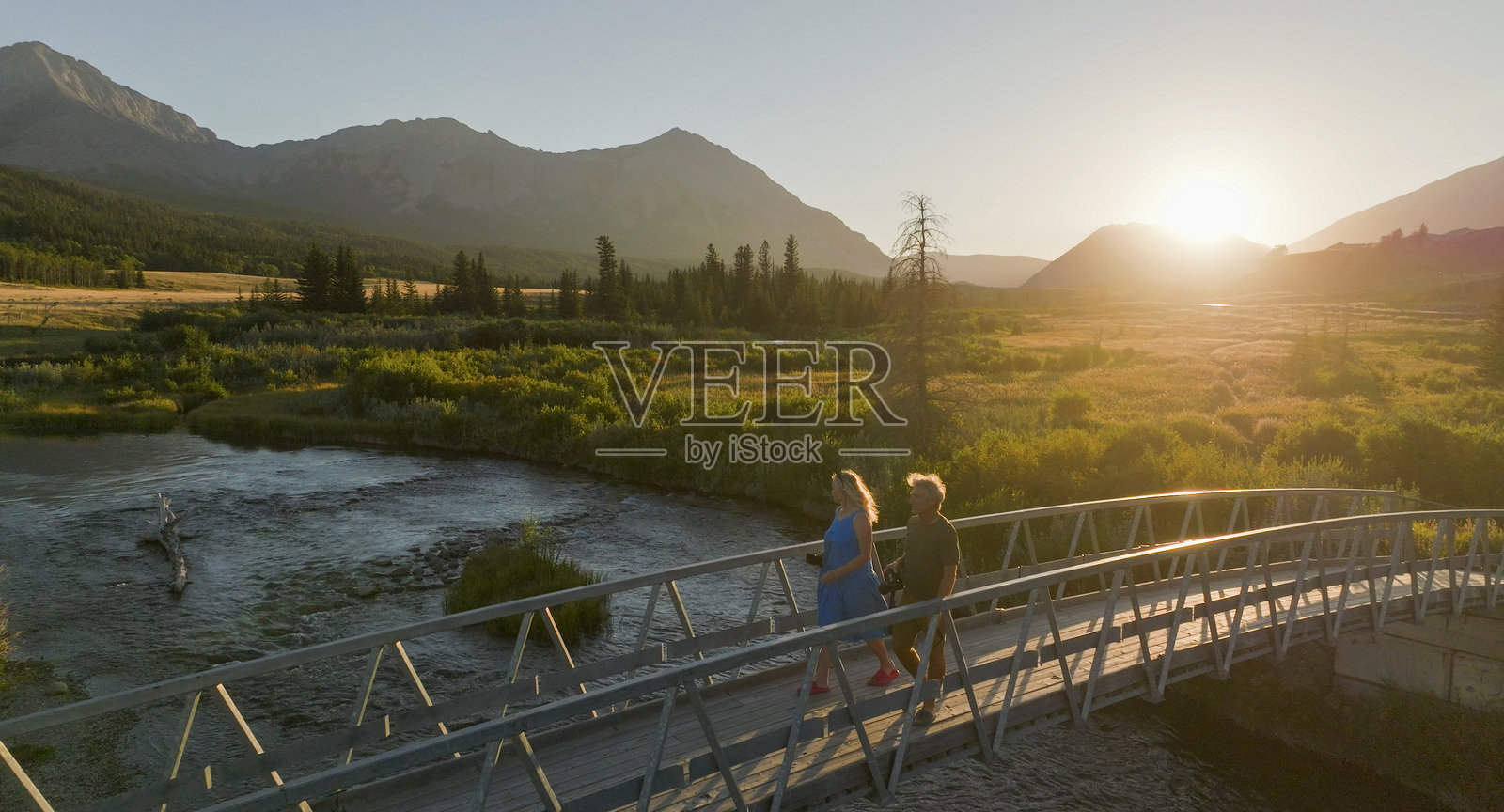 日落时分，成熟夫妇在桥上散步的鸟瞰图照片摄影图片