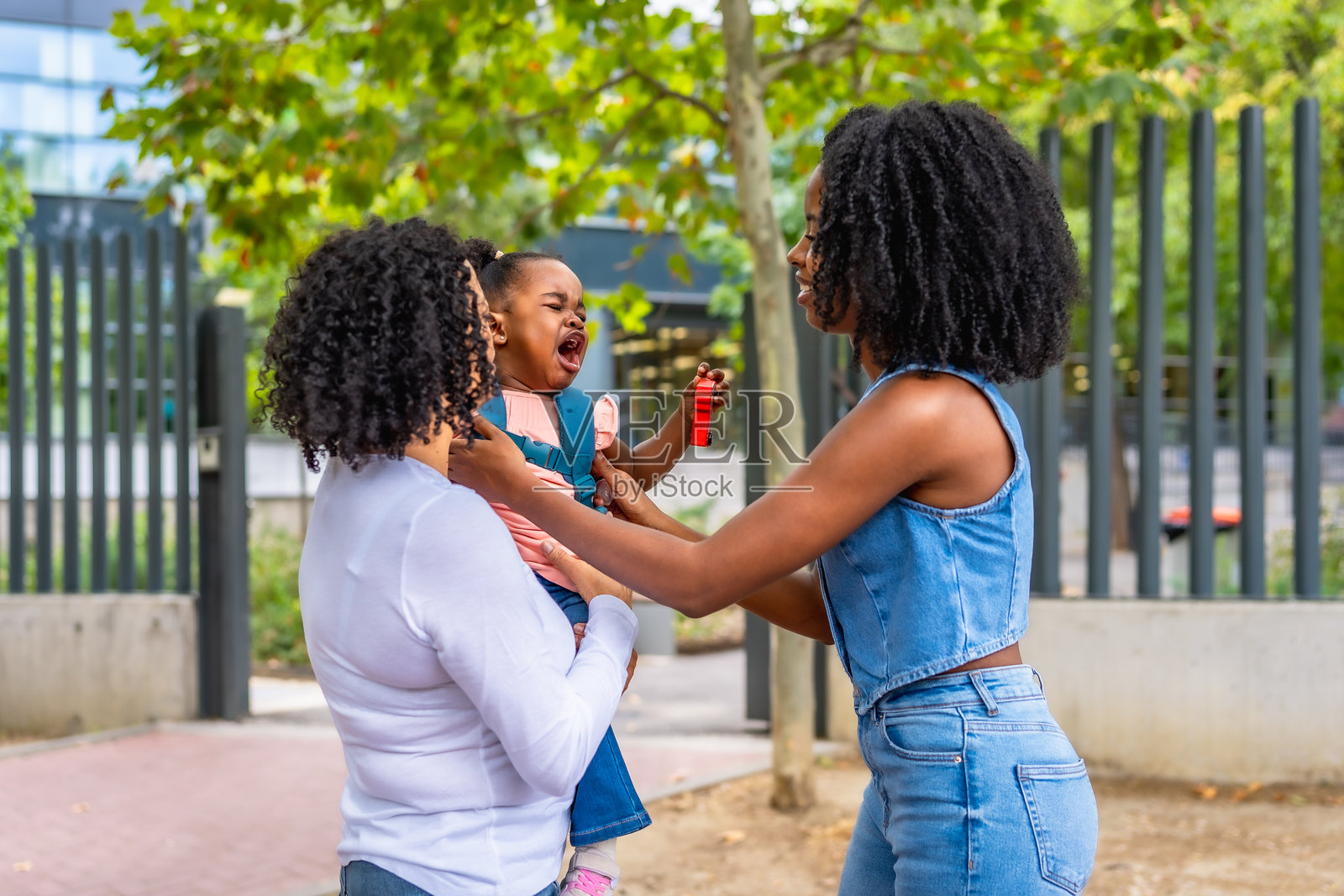 非洲女学生在户外哭泣，身旁是她的母亲和奶奶。照片摄影图片
