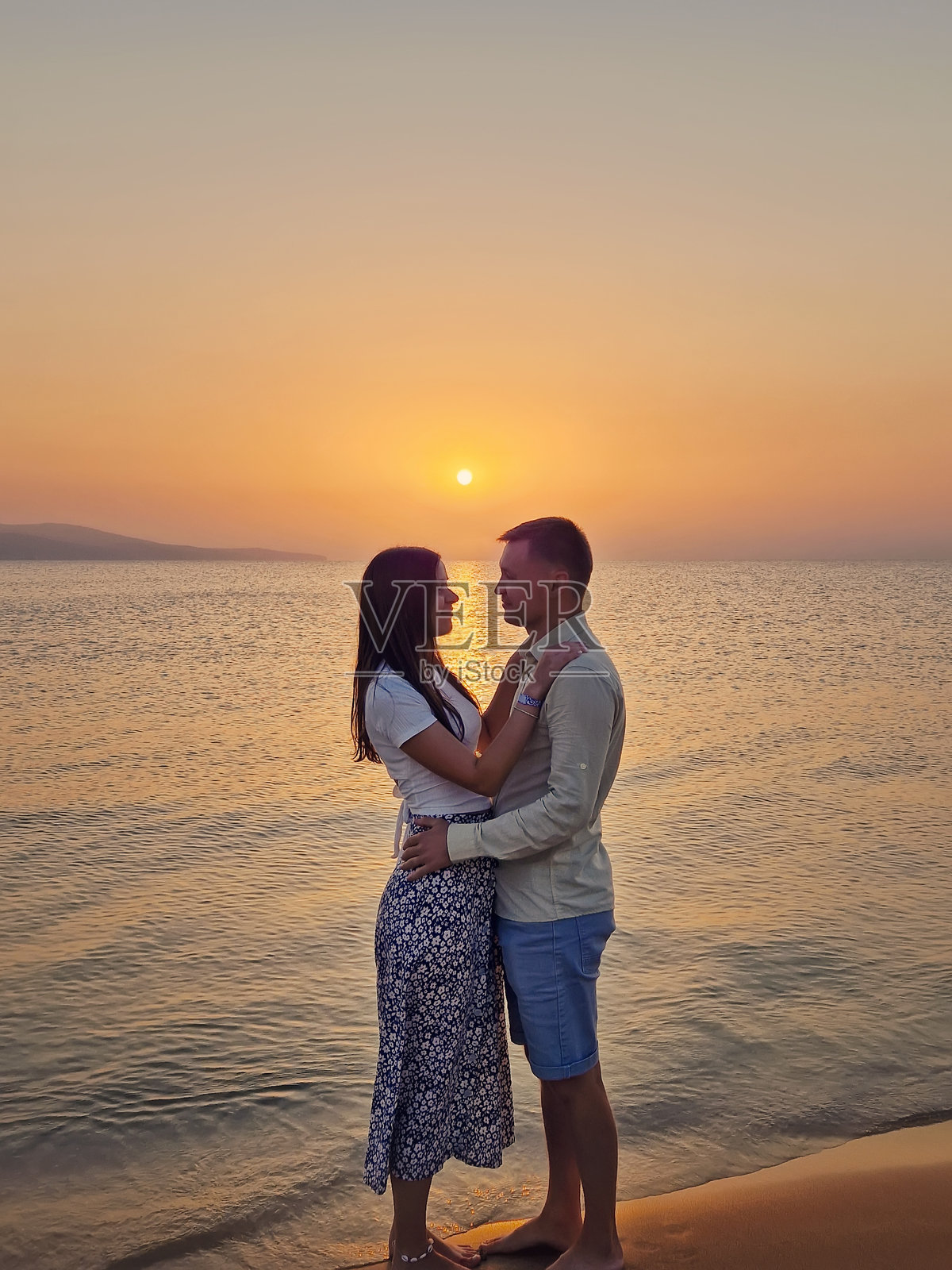 年轻情侣在海边日出时拥抱。新婚夫妻在海滩度蜜月。夏季假期，爱情与浪漫的概念。照片摄影图片