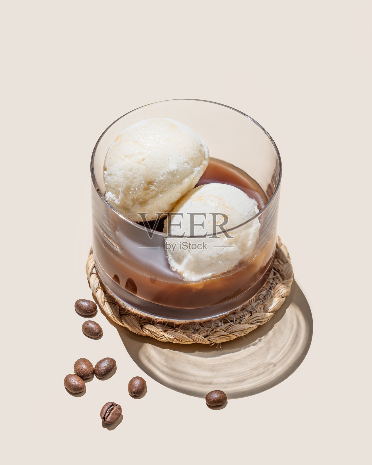 香草冰淇淋球与浓缩咖啡的阿芙佳朵咖啡，盛在玻璃杯中，背景为浅色，周围有咖啡豆和阴影。照片摄影图片