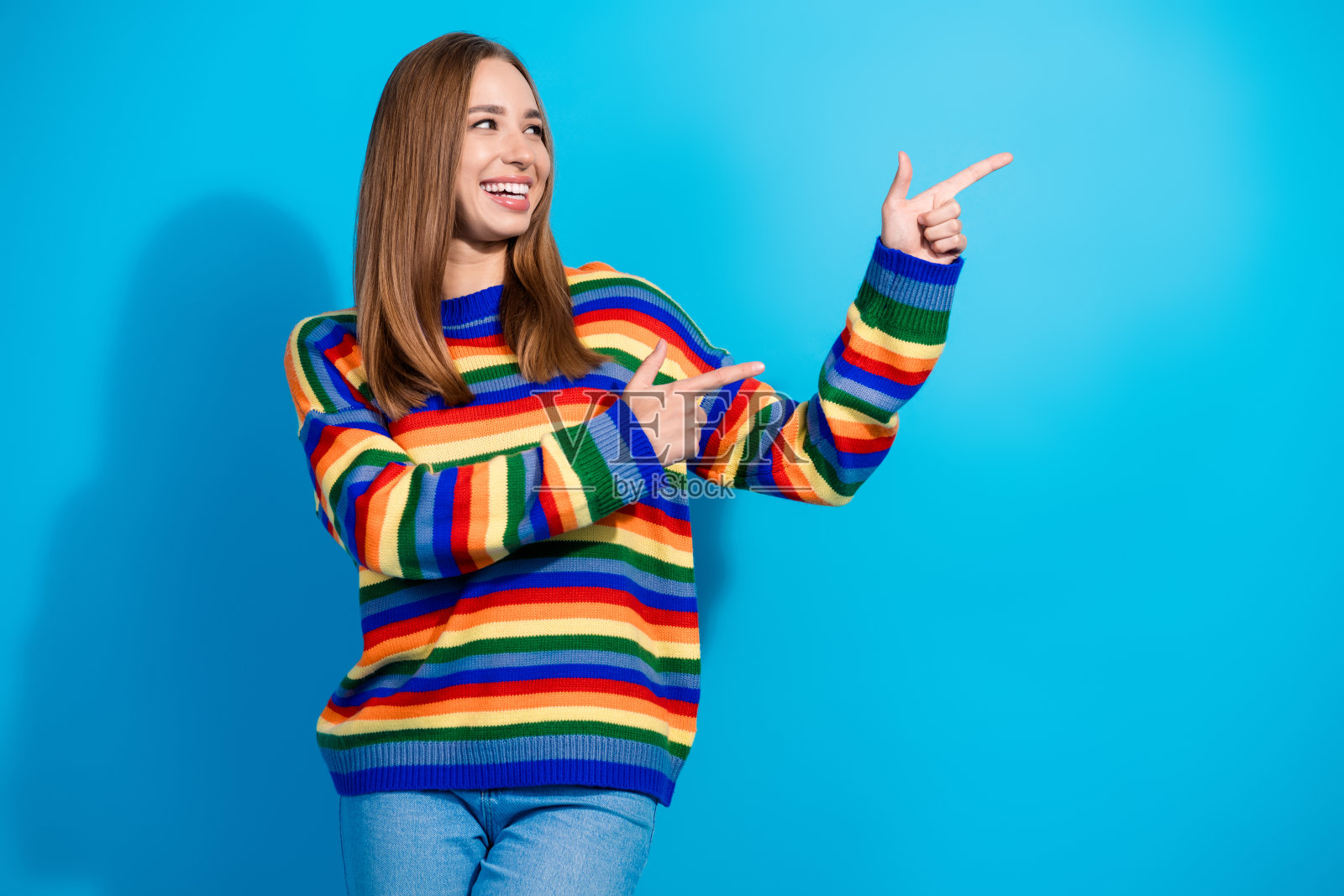 穿着时尚衣服的可爱积极女孩，推荐在蓝色背景下的空白空间。照片摄影图片