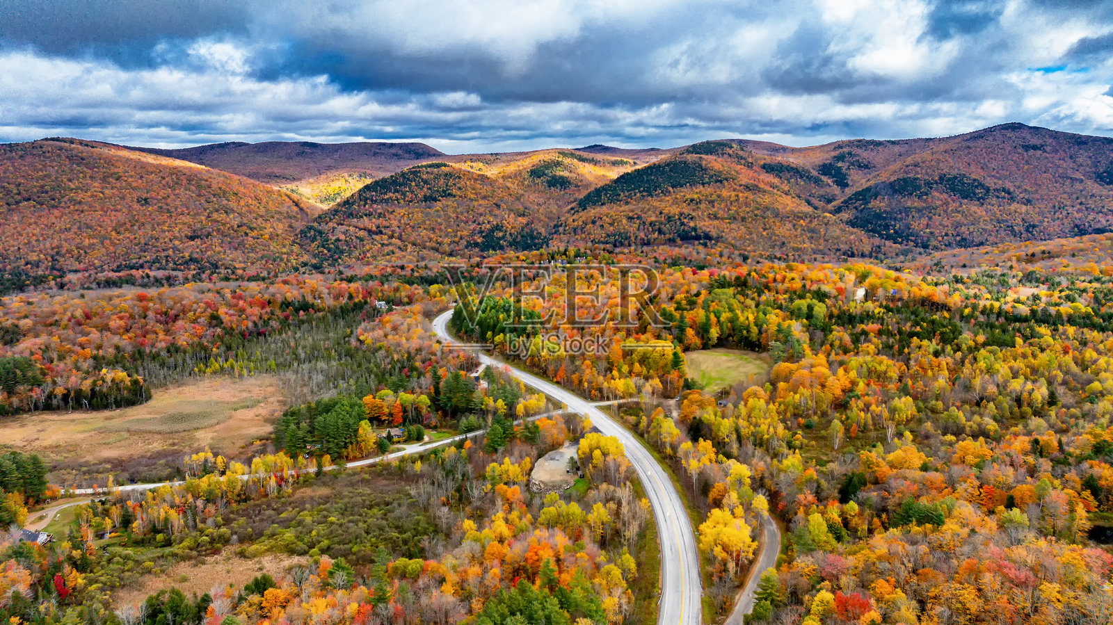 美国的秋天色彩覆盖了山丘。鲜艳的秋叶装点着起伏的山丘，在戏剧性的天空下形成了令人惊叹的风景，展现了大自然的季节之美。照片摄影图片