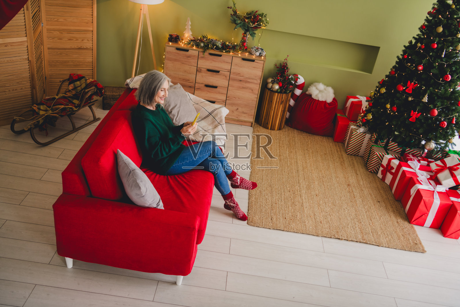 俯视可爱的女孩穿着绿色毛衣，享受室内温馨的圣诞装饰气氛。照片摄影图片