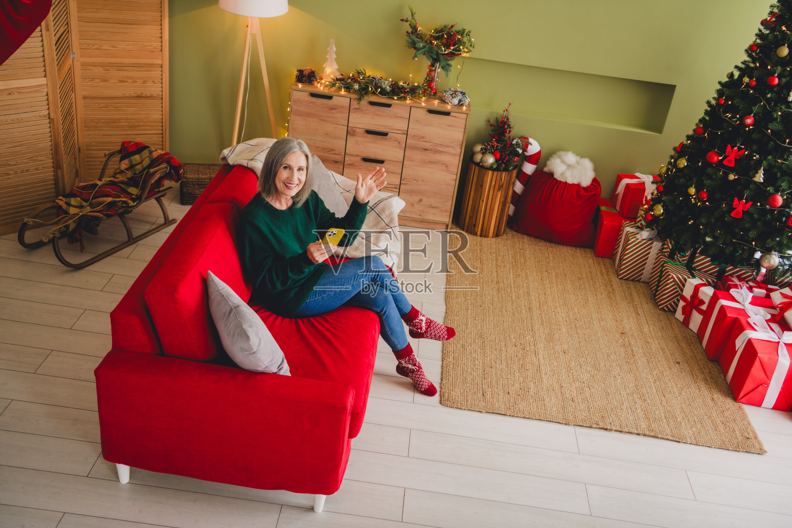 从上方拍摄的快乐退休女性，穿着绿色毛衣，圣诞节时分，室内温馨氛围。照片摄影图片