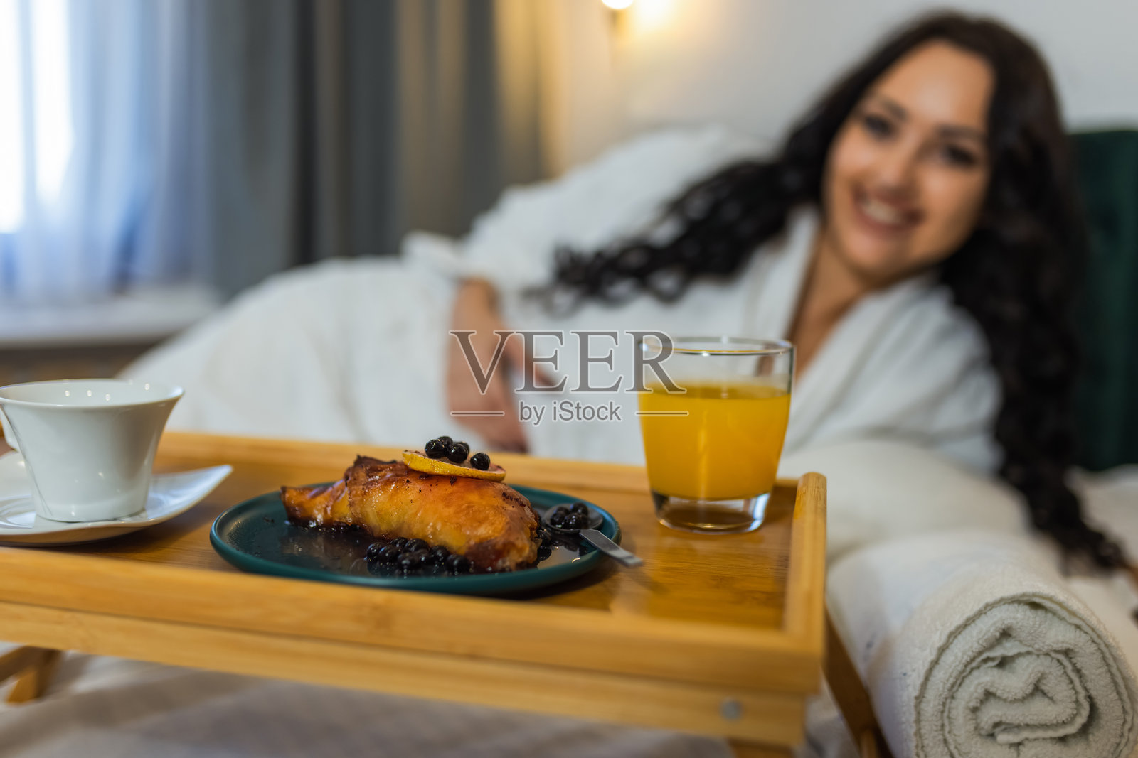 美丽的女人在酒店房间享用早餐，享受假期时光。照片摄影图片