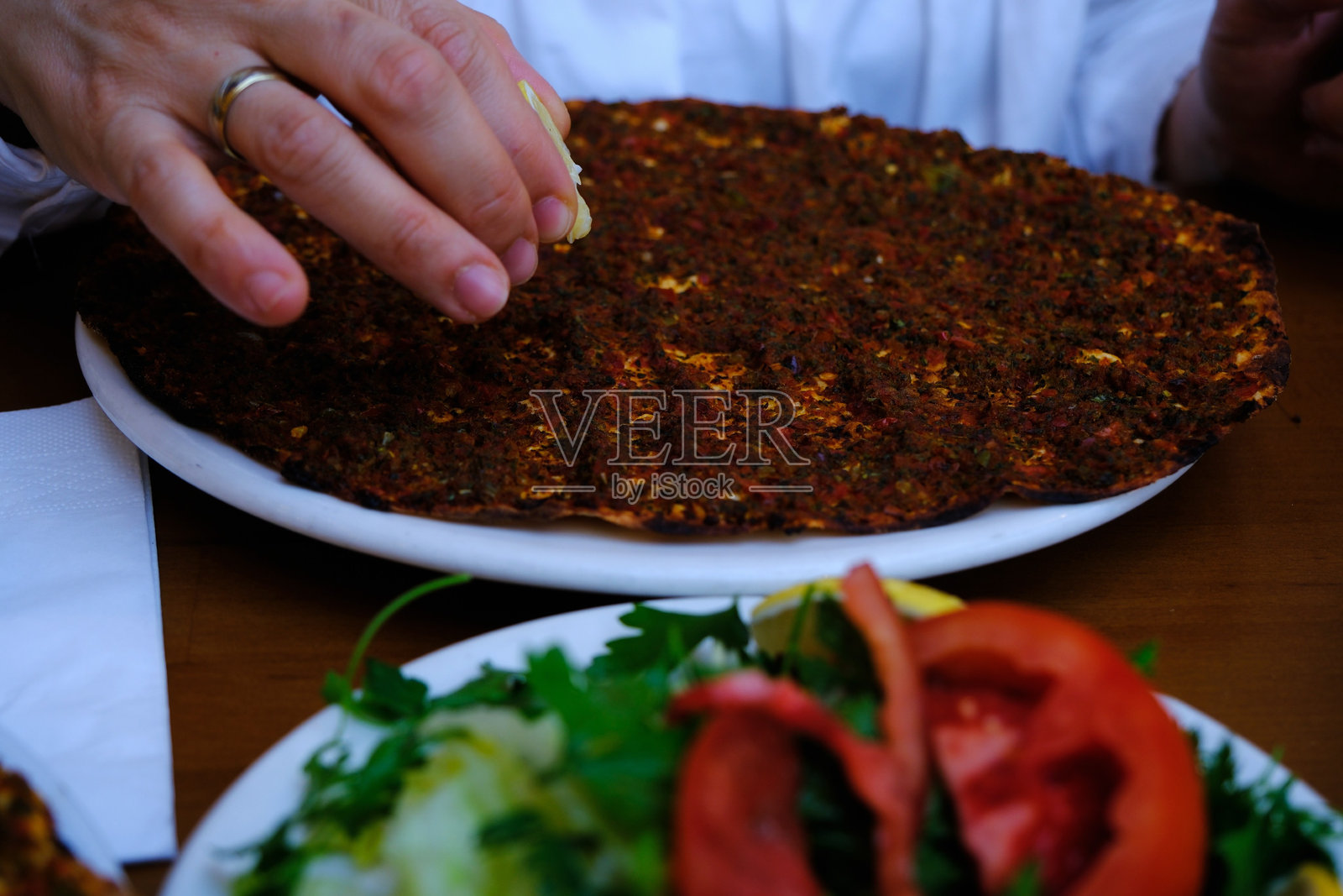 手握柠檬挤汁，浇在传统土耳其美食拉哈马君上照片摄影图片