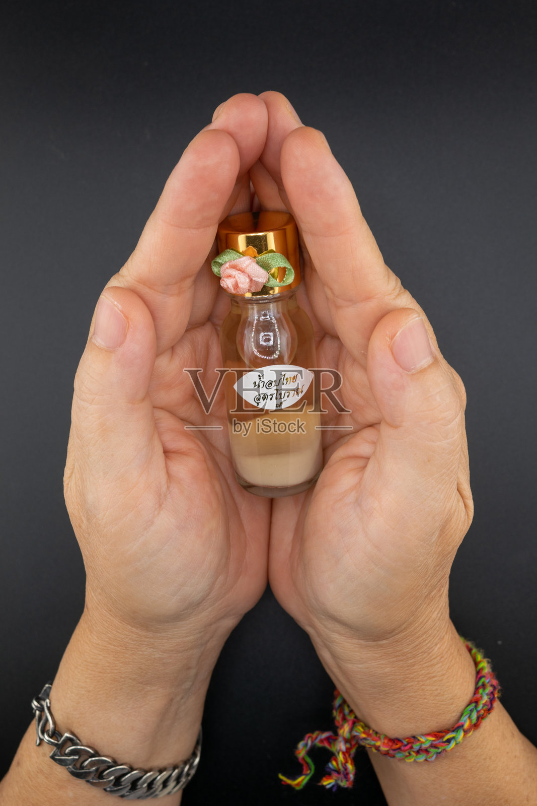 手握金色瓶盖的泰国草本油瓶照片摄影图片