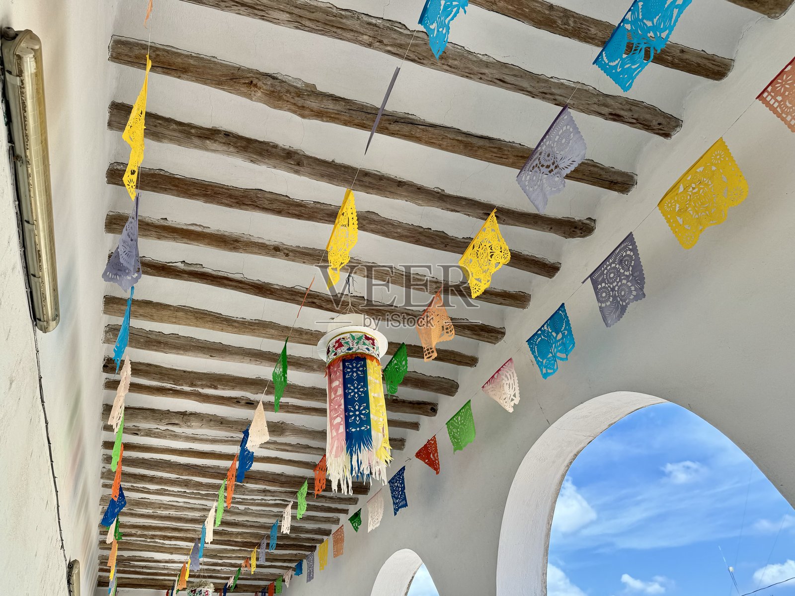 墨西哥乌艾马圣多明各·古兹曼修道院的拱廊中悬挂着五彩斑斓的旗帜照片摄影图片