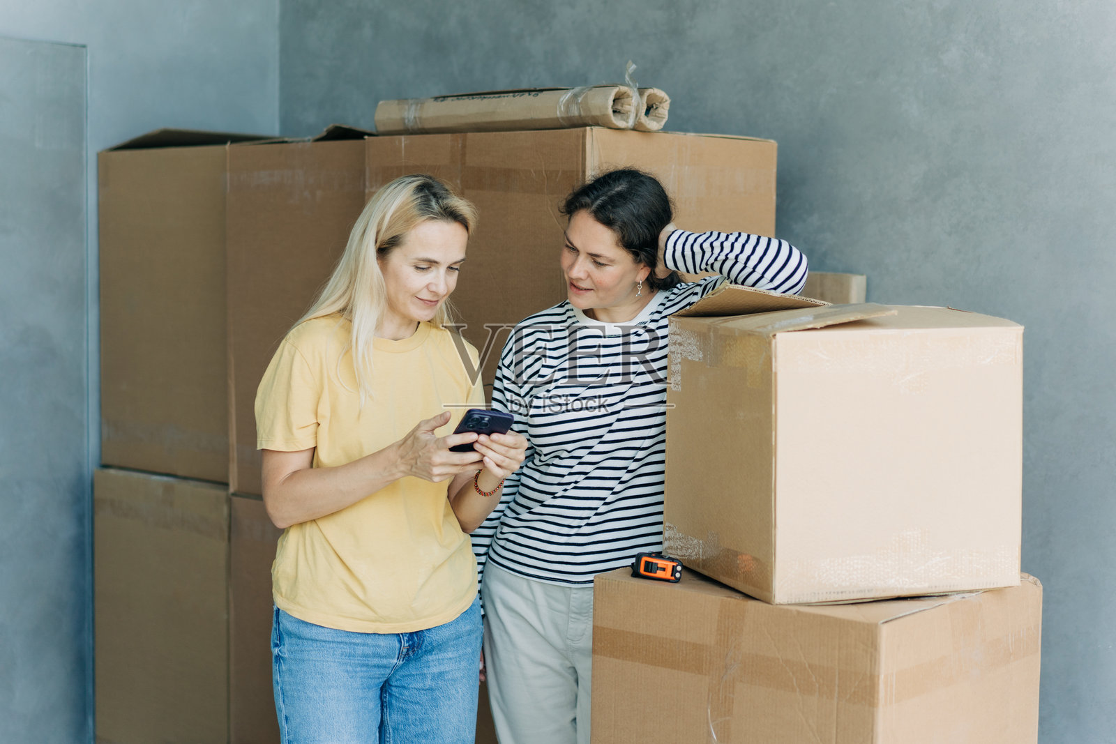 两位女性正在搬家，打电话给物流公司安排货物运输。照片摄影图片