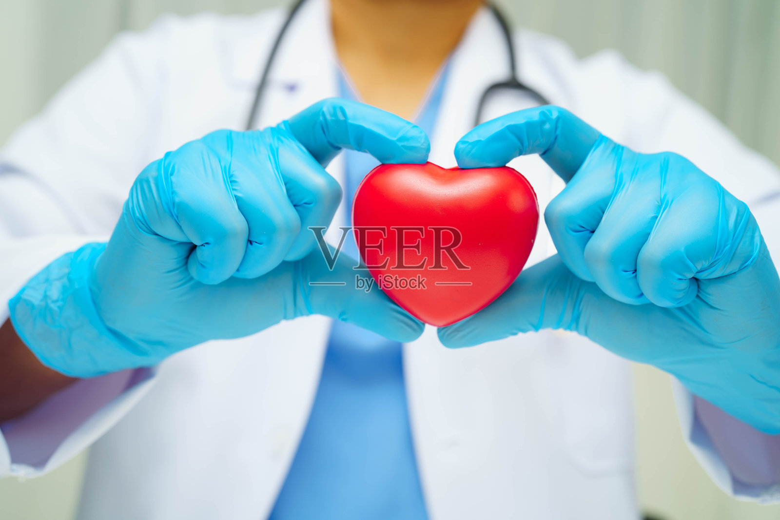 亚洲女性医生在医院里手持红色心形图案，象征健康。照片摄影图片