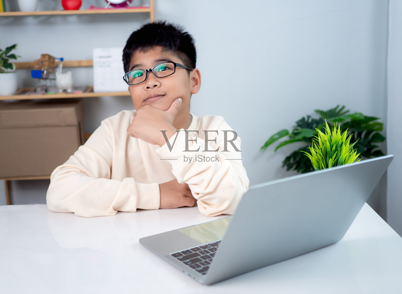 亚洲男学生在使用电脑思考。科技教育概念，居家学习，展现现代教育生活方式。来自学校老师的虚拟在线课堂。照片摄影图片