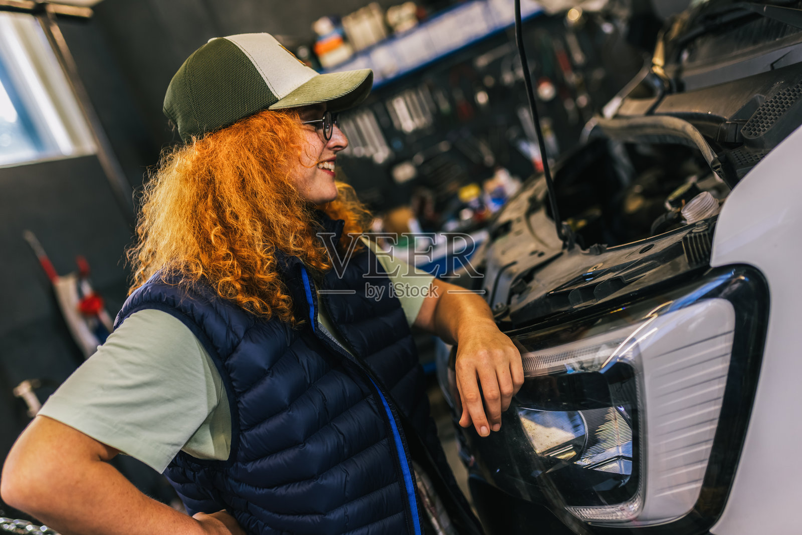年轻的红发女性机械师正在修理一辆长车，卡车，挖掘机。照片摄影图片