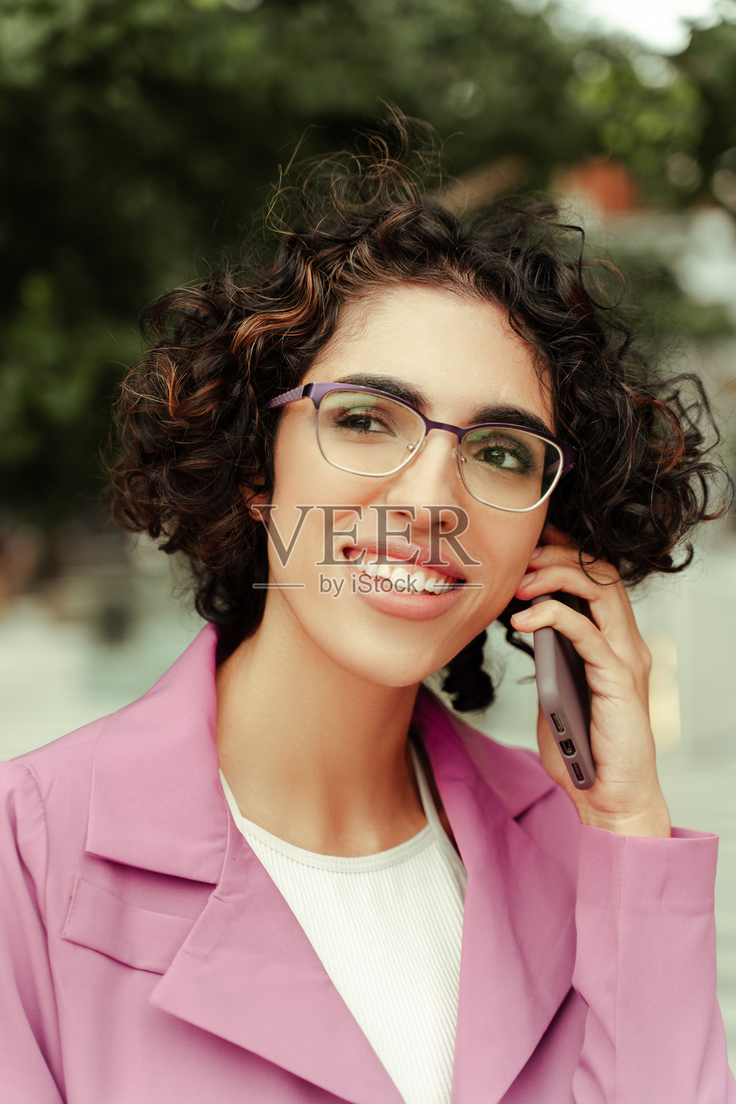 在户外使用智能手机交谈和微笑的年轻职场女性照片摄影图片