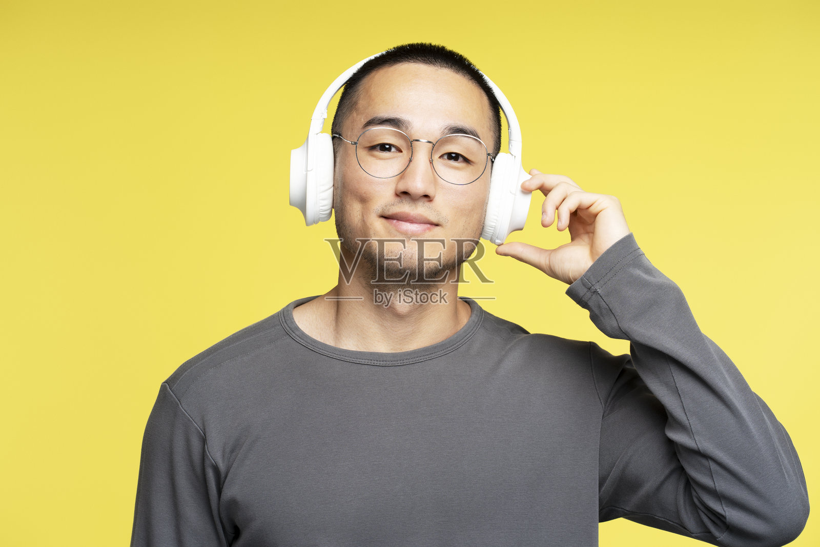 年轻男子在黄色背景下戴着耳机听音乐照片摄影图片