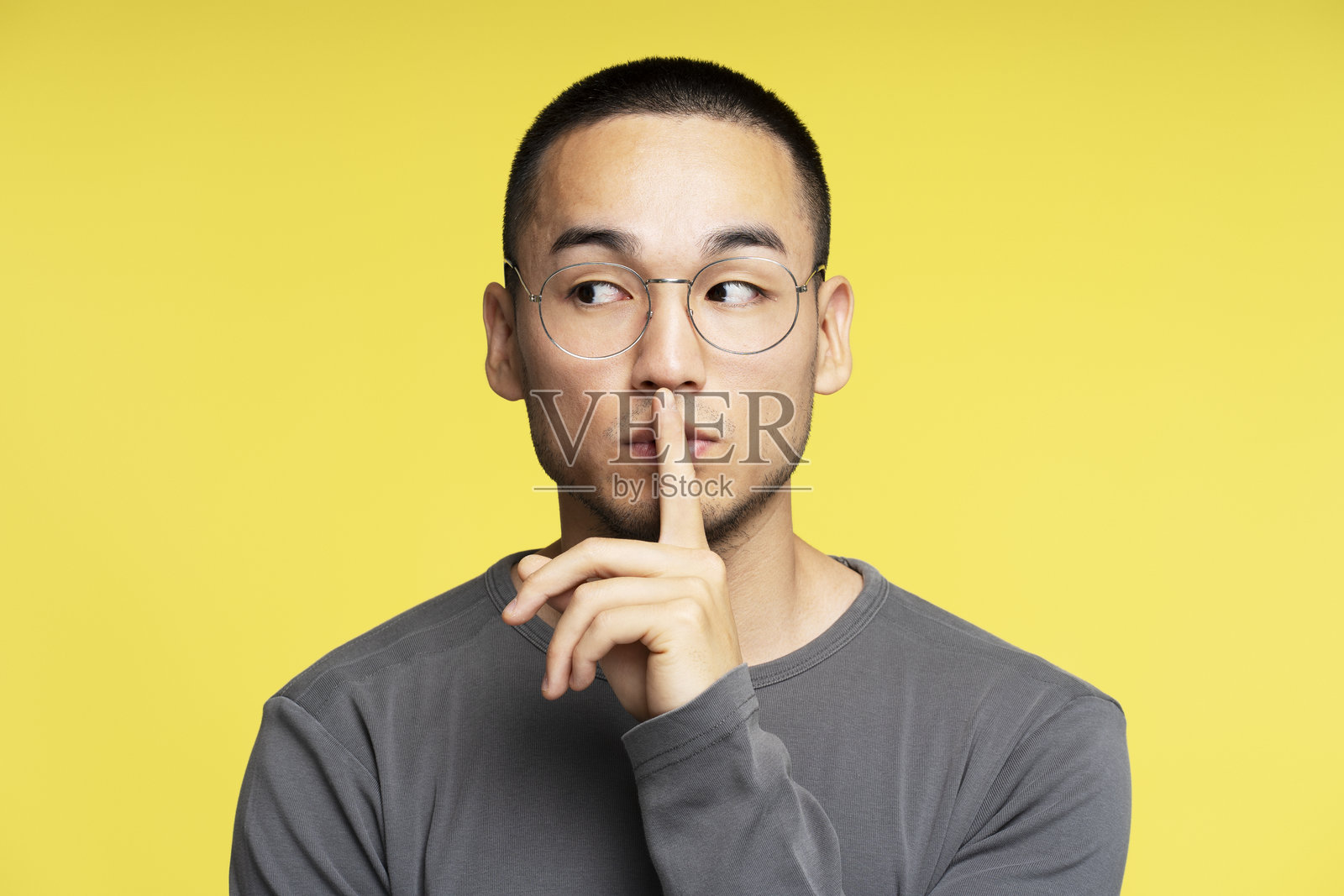 年轻男子用手指在嘴唇上做出安静的手势照片摄影图片