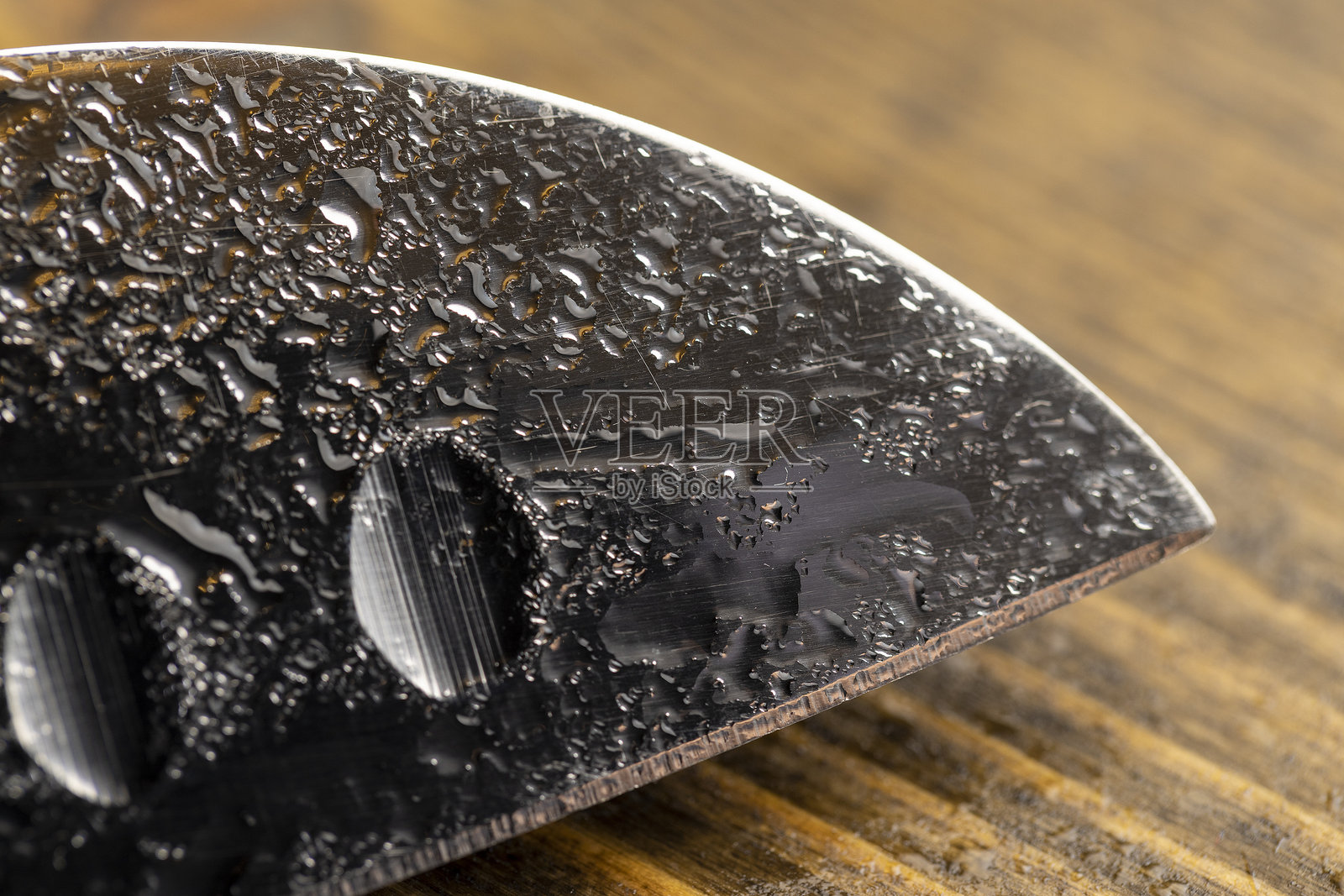 一把沾满水珠的钢刀，背景为黑板。照片摄影图片