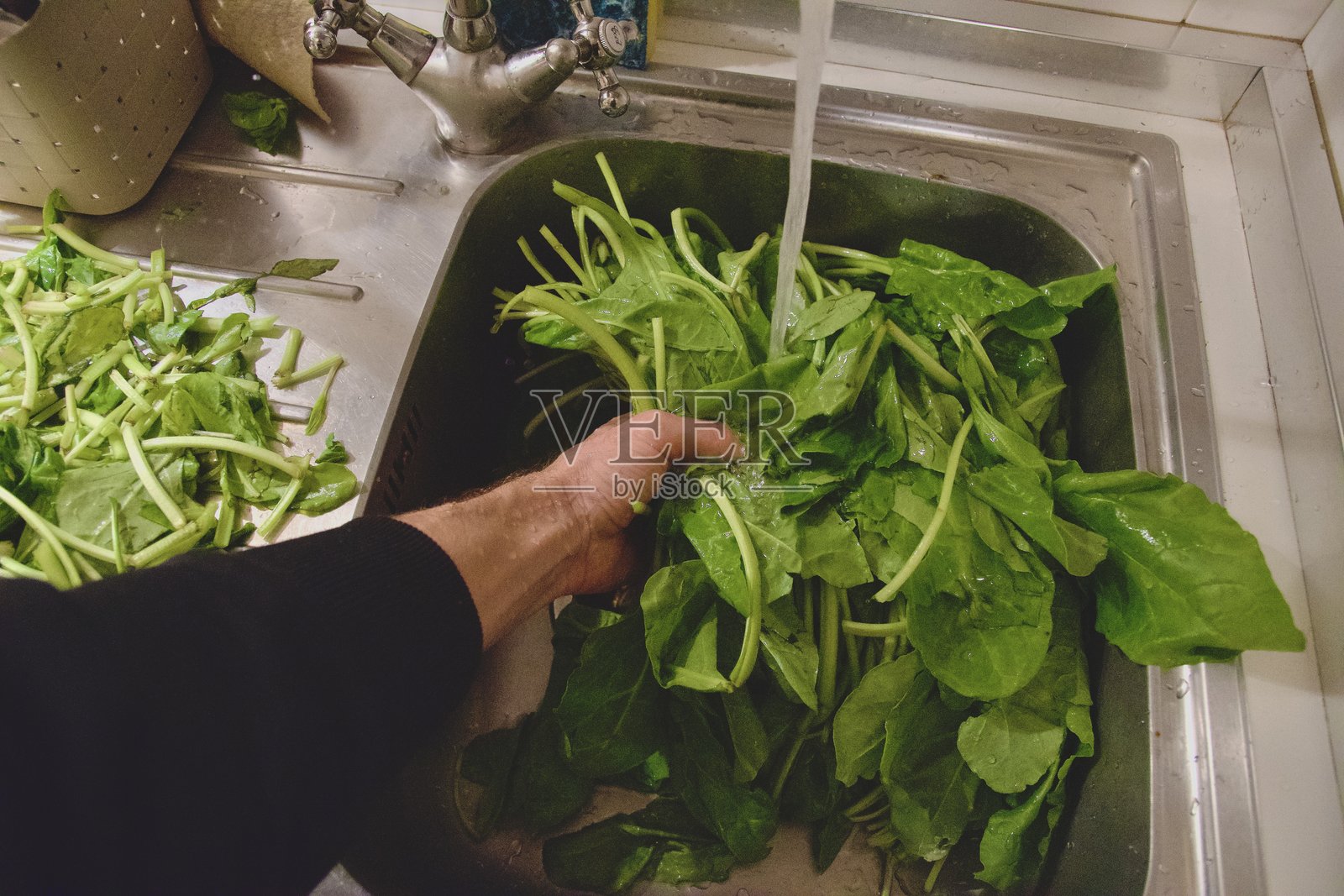 男人的手在清洗蔬菜，准备菠菜，使用刀切去菠菜的尖端。照片摄影图片