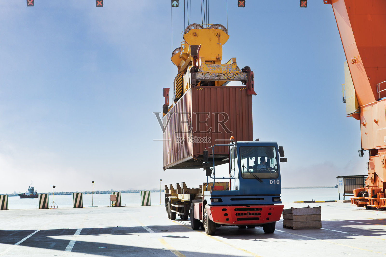 起重机在港口吊起集装箱并装载到卡车上。照片摄影图片