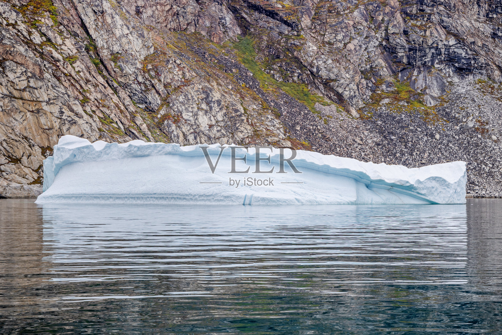 冰山漂浮在岩石墙前照片摄影图片