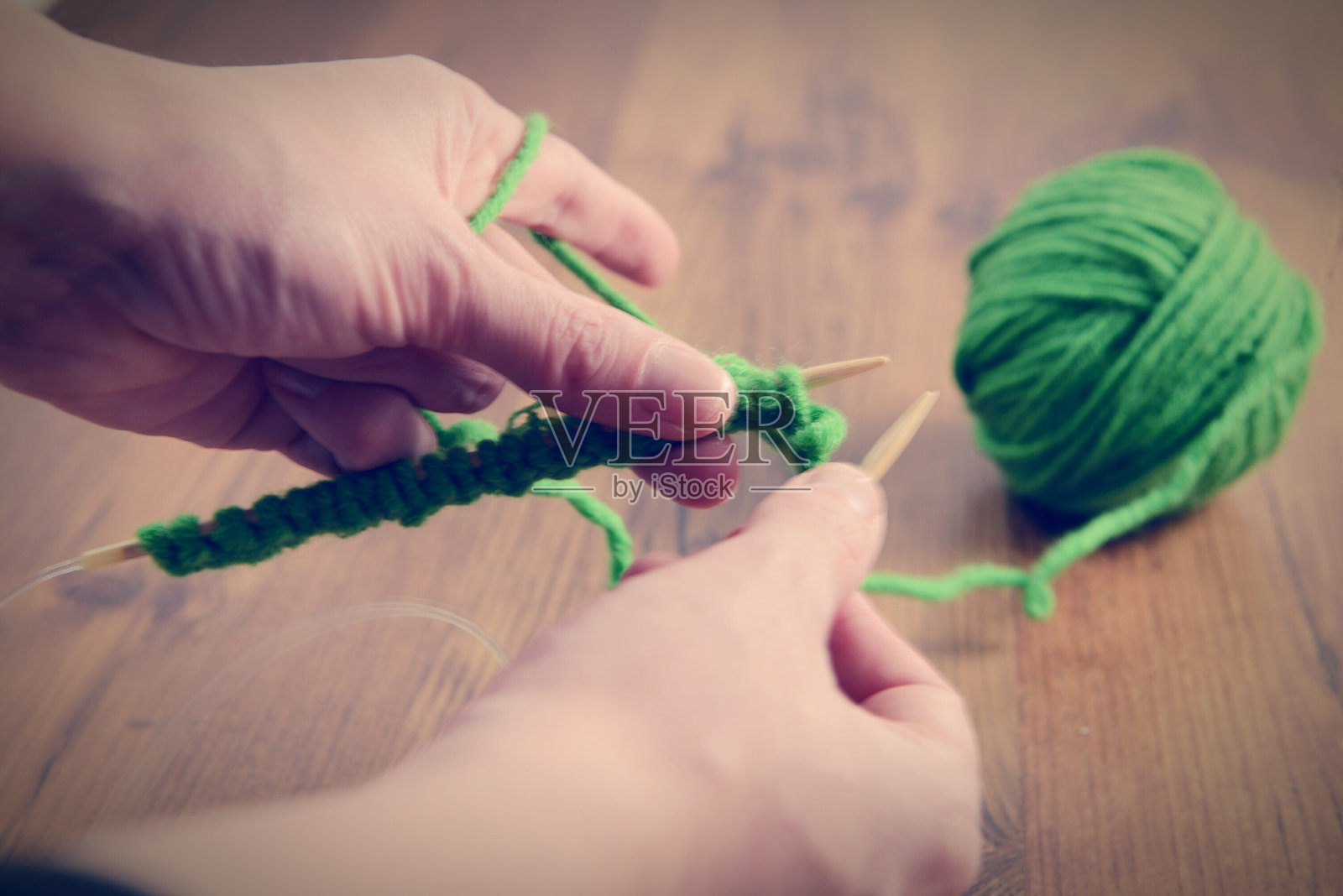 在家中桌子上编织绿色毛线的手部特写照片摄影图片
