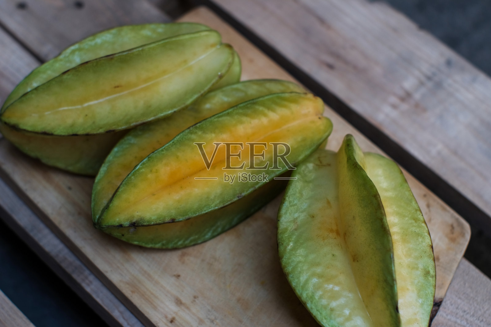 三颗完整的杨桃（又称星果、五角果）放在木质切菜板上照片摄影图片