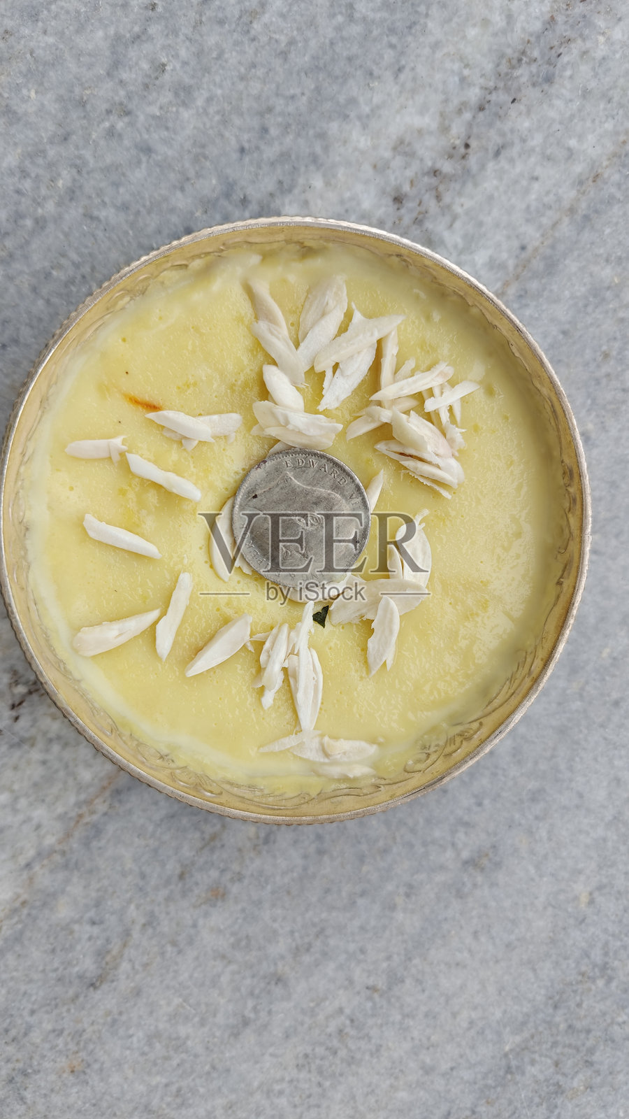 精致的藏红花杏仁米布丁，搭配历史银币，盛放在纯银碗中照片摄影图片