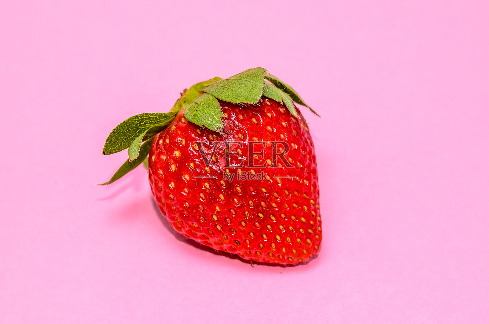 一颗顶部有绿叶的红色草莓照片摄影图片