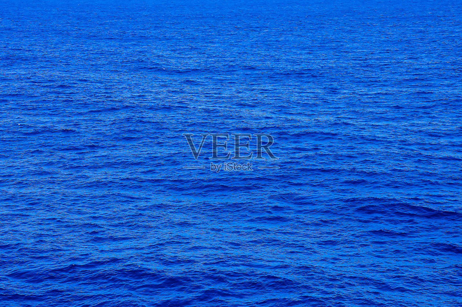 海洋呈现深蓝色，没有涟漪或波浪。照片摄影图片