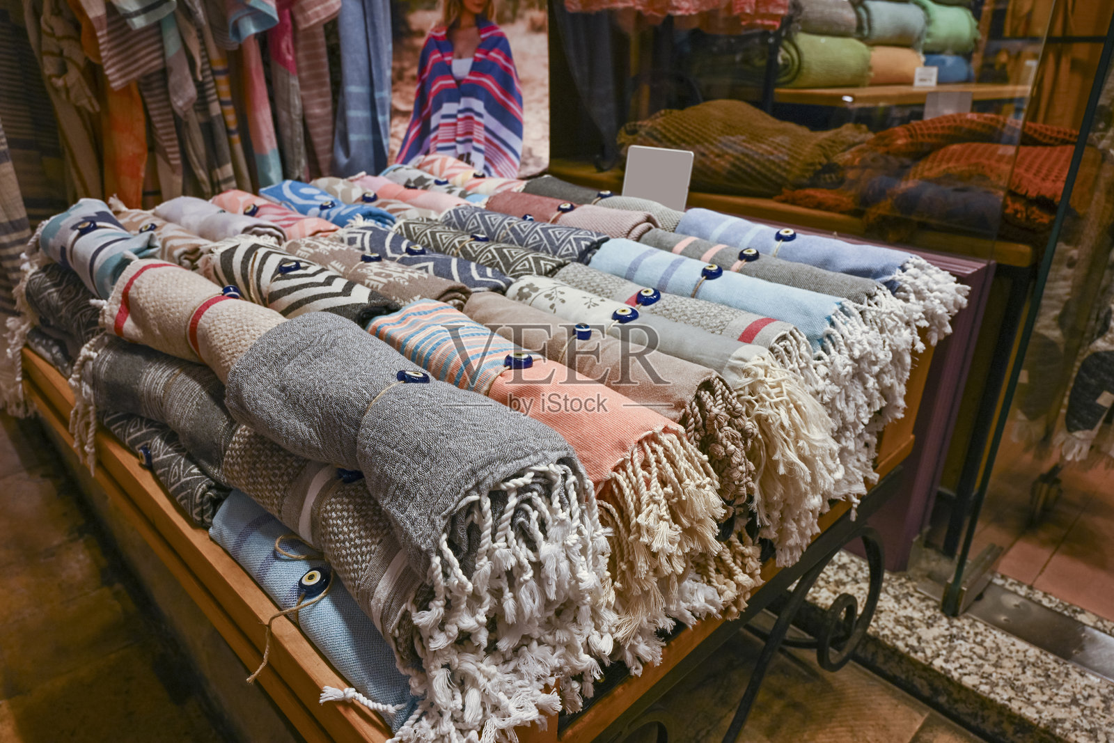 在土耳其伊斯坦布尔的传统市场上，商店前的摊位上摆放着装饰有邪眼珠子的手工编织毛巾卷。照片摄影图片