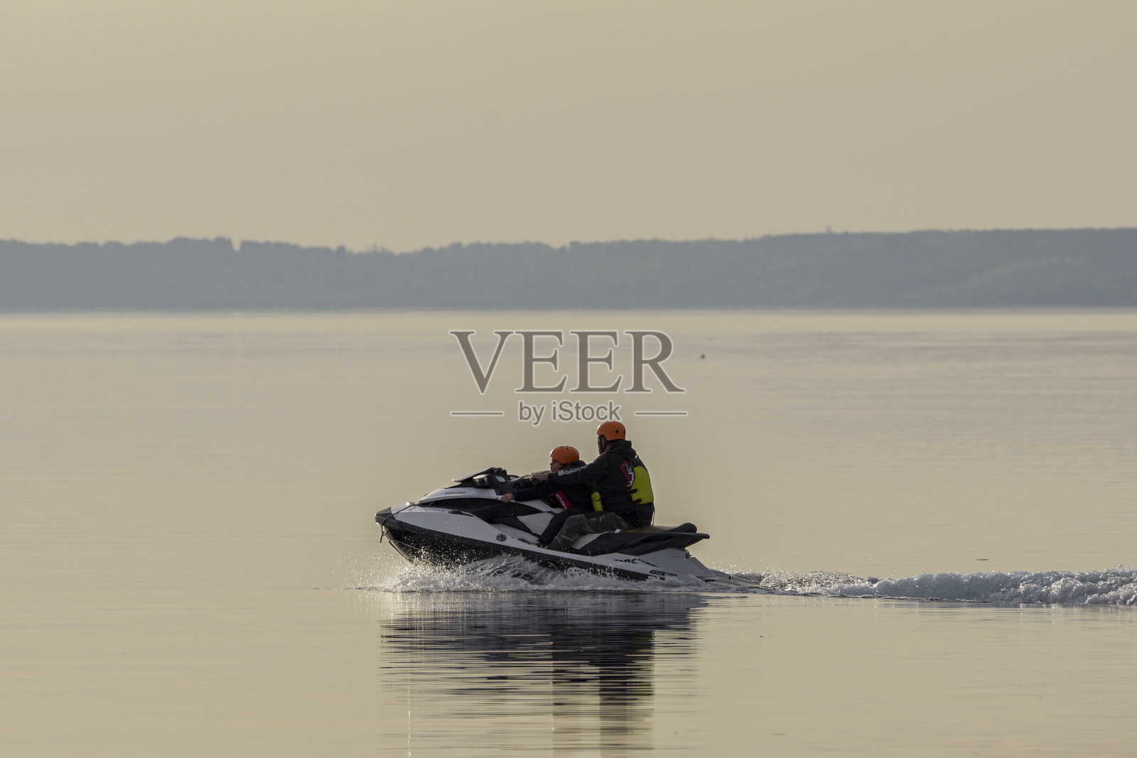 父亲和儿子在湖上清晨使用水上滑水板。智利阿劳卡尼亚普孔，2024年10月7日。照片摄影图片