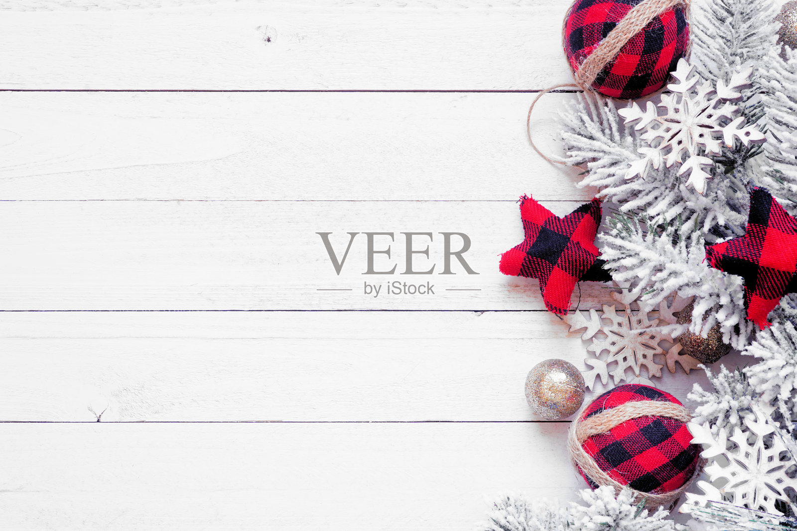 红黑格子装饰品、雪白的树枝和金色球饰的圣诞边框。俯视白色木质背景。留白空间。照片摄影图片