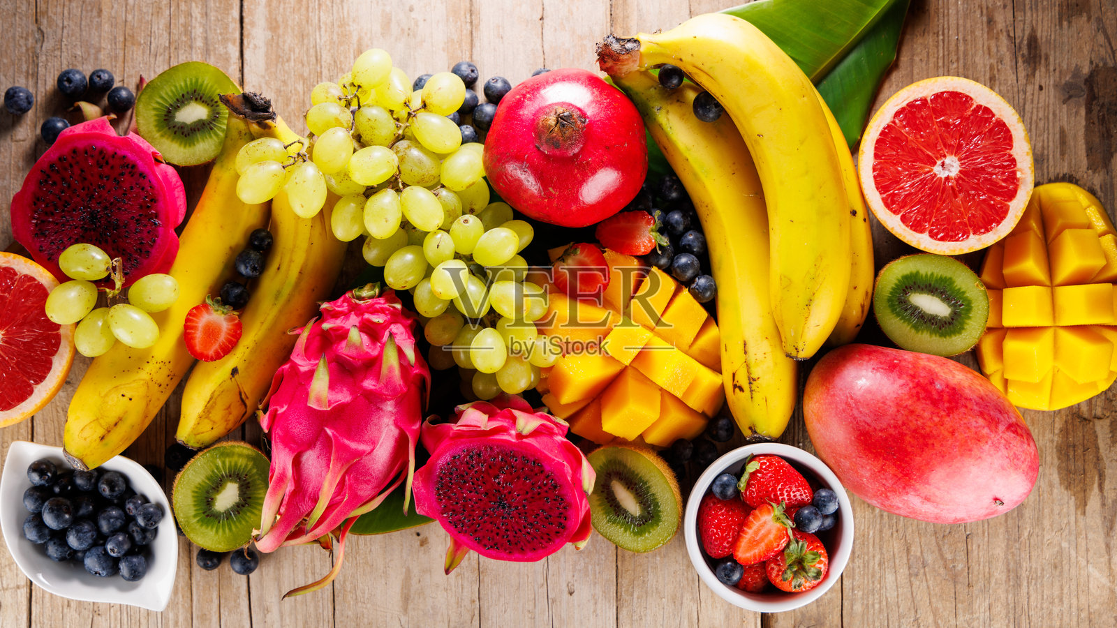 异国水果和热带棕榈叶在木质背景上照片摄影图片