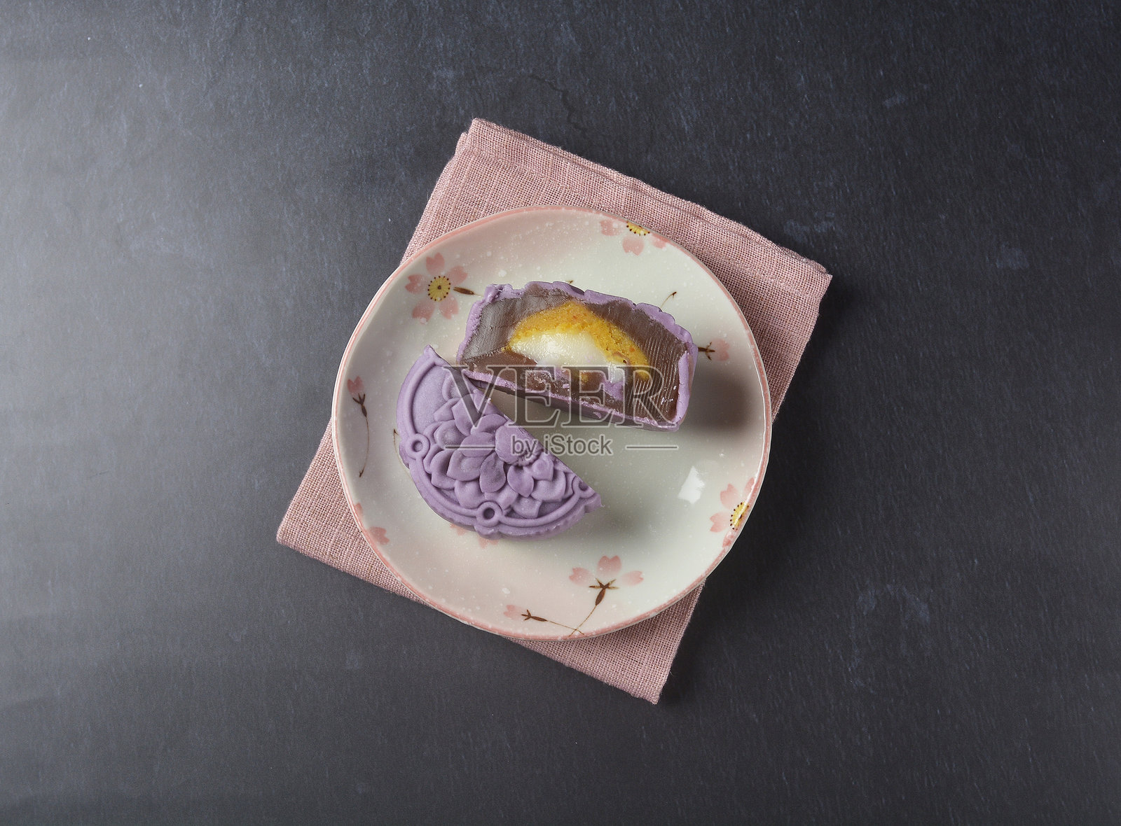 优质紫色粉色可爱健康的烤莲蓉月饼，内含蛋黄和麻糬，呈玫瑰花3D形状，放在黑色桌灯中，适合秋季节日的清真亚洲甜点菜单咖啡馆。照片摄影图片