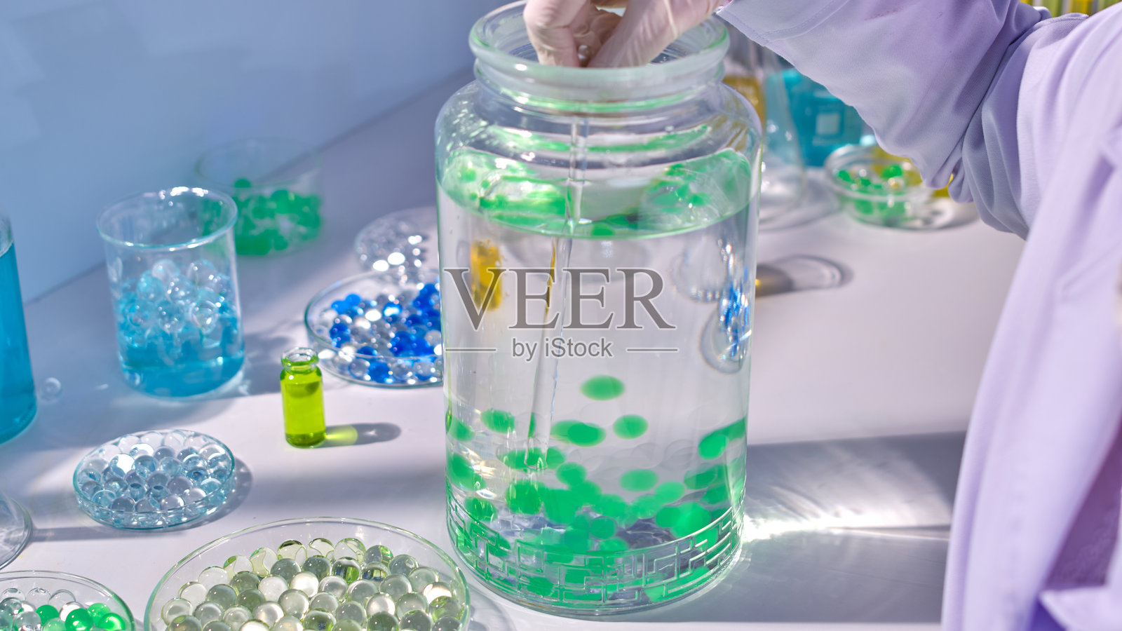 高角度拍摄的白色实验室桌面照片，展示了一个装有水和水球的大玻璃花瓶。创意设计模板，留有空白文本空间。照片摄影图片