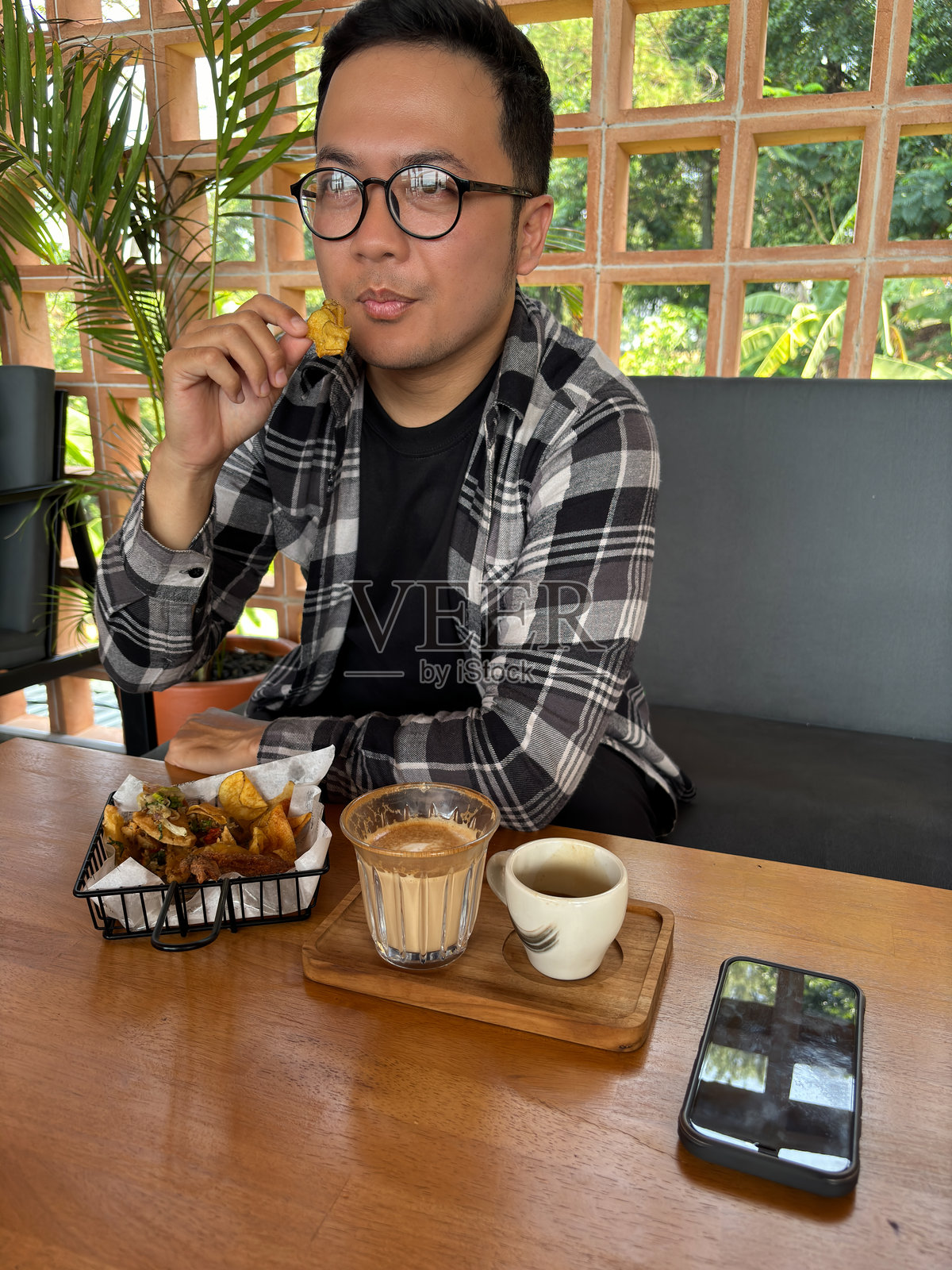 男人坐在咖啡馆里，桌上放着小吃和咖啡。照片摄影图片