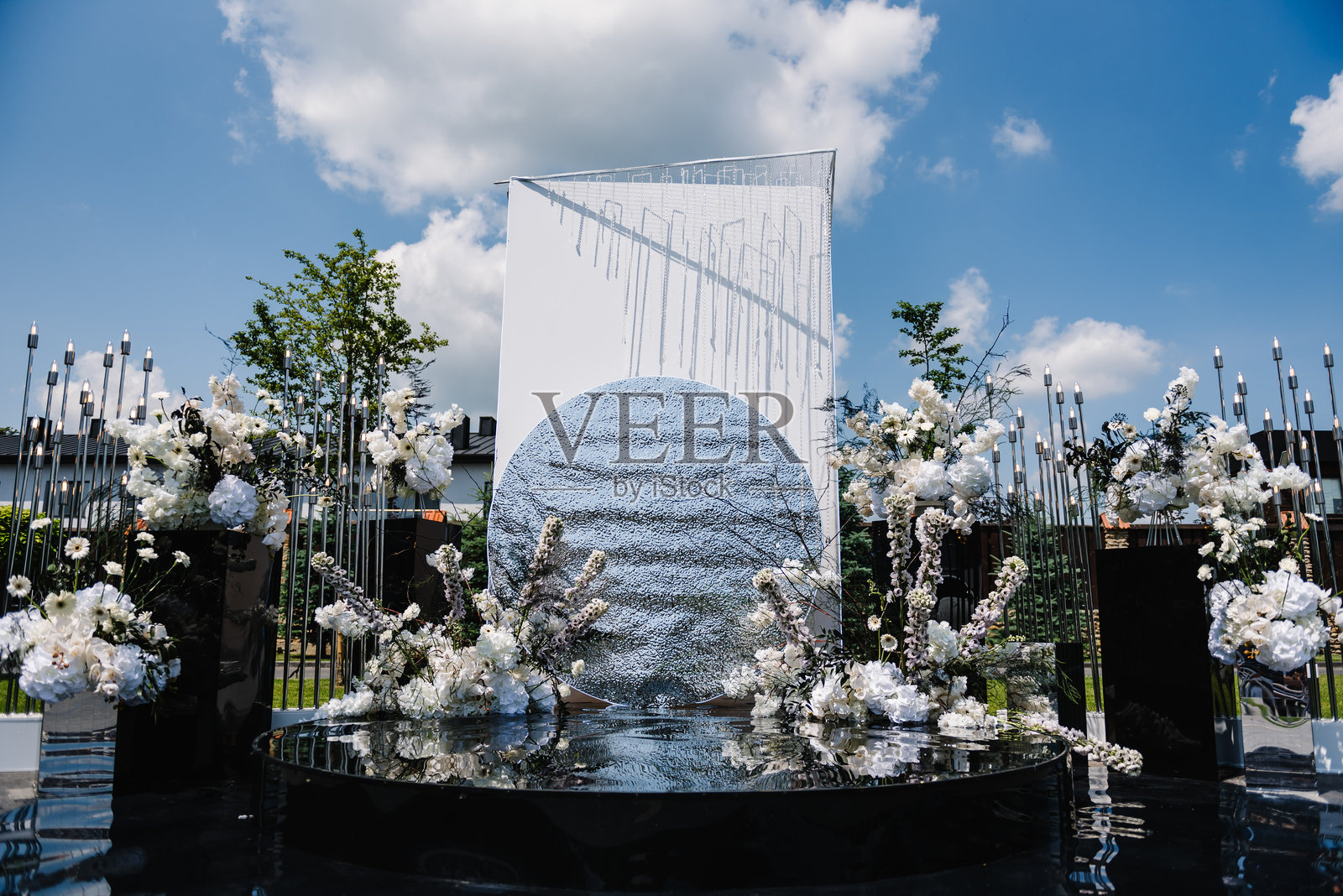 举行婚礼的地点。婚礼装饰。后院宴会区新婚夫妇的舞台或领奖台。豪华拱门，银墙装饰鲜花和绿色，绿色植物，花环。前视图。照片摄影图片