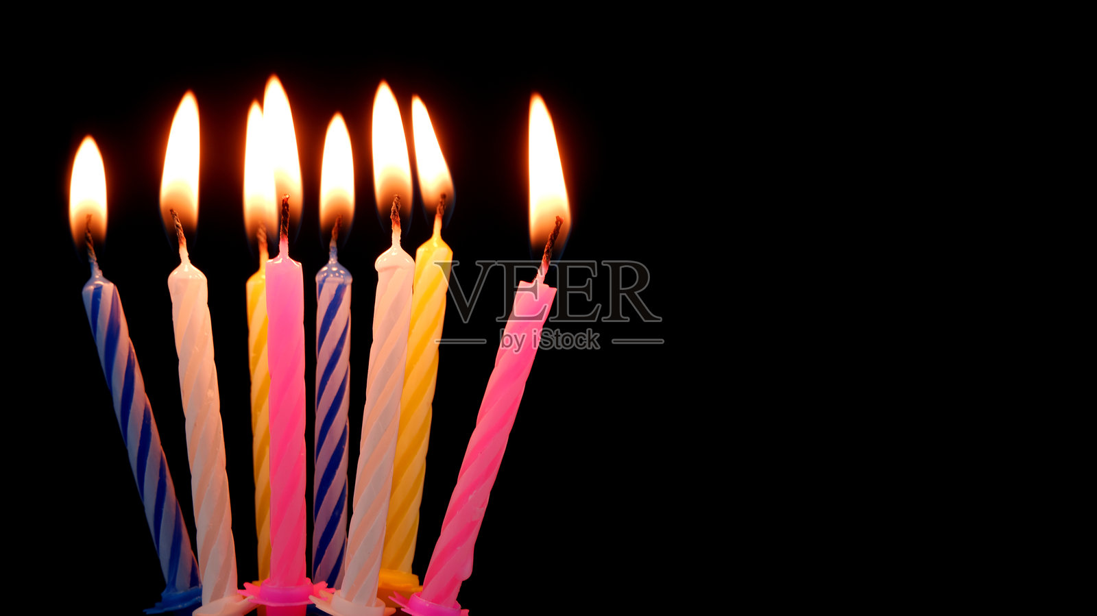 生日蜡烛在黑色背景上燃烧。照片摄影图片