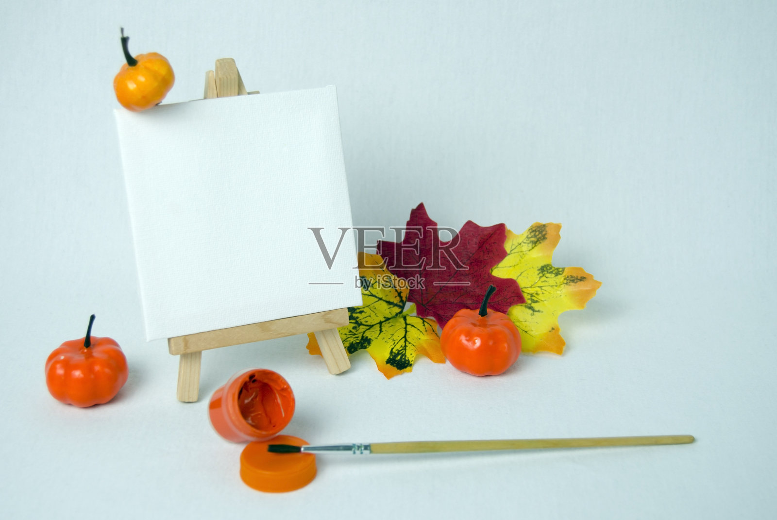 迷你画架上放着白色空白画布。艺术概念。万圣节概念。秋季概念。白色背景。照片摄影图片